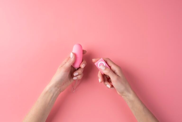 A vibrating love egg in someone's hands on a pink background