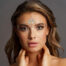 Close-up of a woman with crystal face jewels arranged on her forehead and temples for a fashion look.