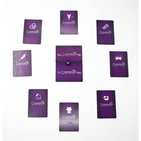 DOMIN8CGx3jpg Purple Domino card game spread on white surface with a central stack and a die on top; cards show logos and icons.