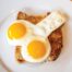 Two sunny-side-up eggs on a slice of toasted bread on a white plate and ready to eat.