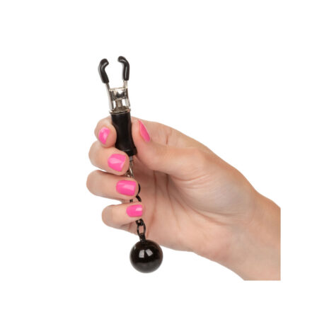 SE-2551-20-2x2jpg Hand holding a small metal clamp with a chain and black ball weight; pink nails on the fingers.