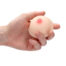 Close-up of a hand squeezing a small silicone breast model with a pink nipple.