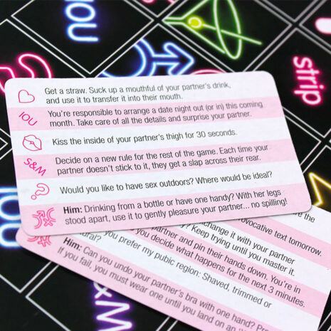 SMTSx4jpg Set of pink prompt cards from a sexual intimacy game, showing cheeky prompts and icons on a neon board backdrop.