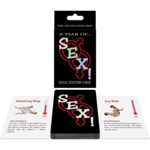 A black card deck titled 'A Year of Sex! Sexual Position Cards' with male/female symbols intertwined on the cover, shown with open cards on a white surface.