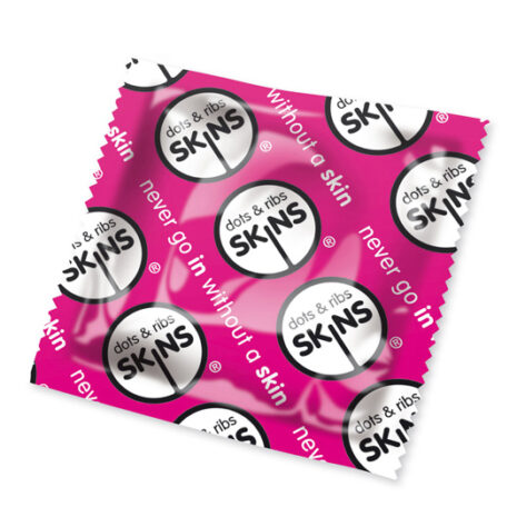 Pink condom wrapper with white circular SKINS logos and 'dots & ribs' slogan repeated across the surface.
